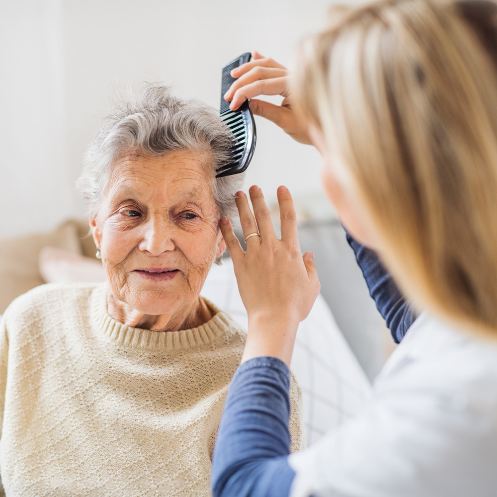 Stationäre Pflege im Seniorenhaus „Regenbogen“ Cottbus – persönliche Rundum‑Betreuung Pflegerin kämmt einer älteren Dame liebevoll die Haare im Seniorenhaus „Regenbogen“ in Cottbus – stationäre Pflege, umfassende Versorgung und Erhalt der Lebensqualität.